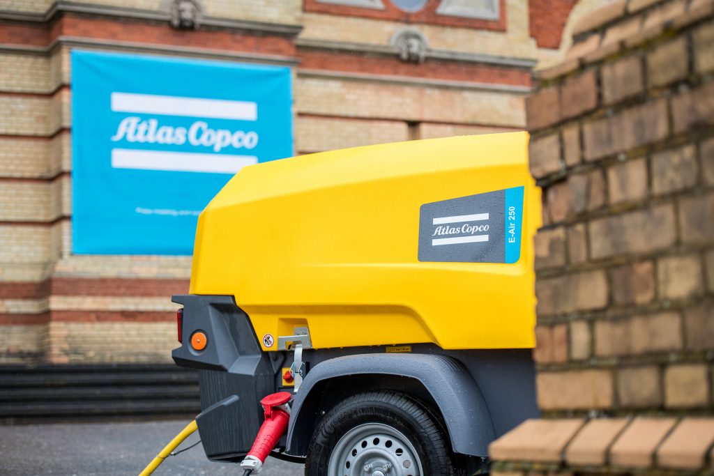 E air kompressor i bruk framför atlas copcos logga